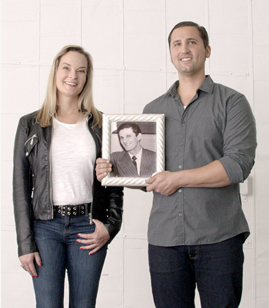 Katherine and Eric standing next to each other with picture of Eric's ancestor.